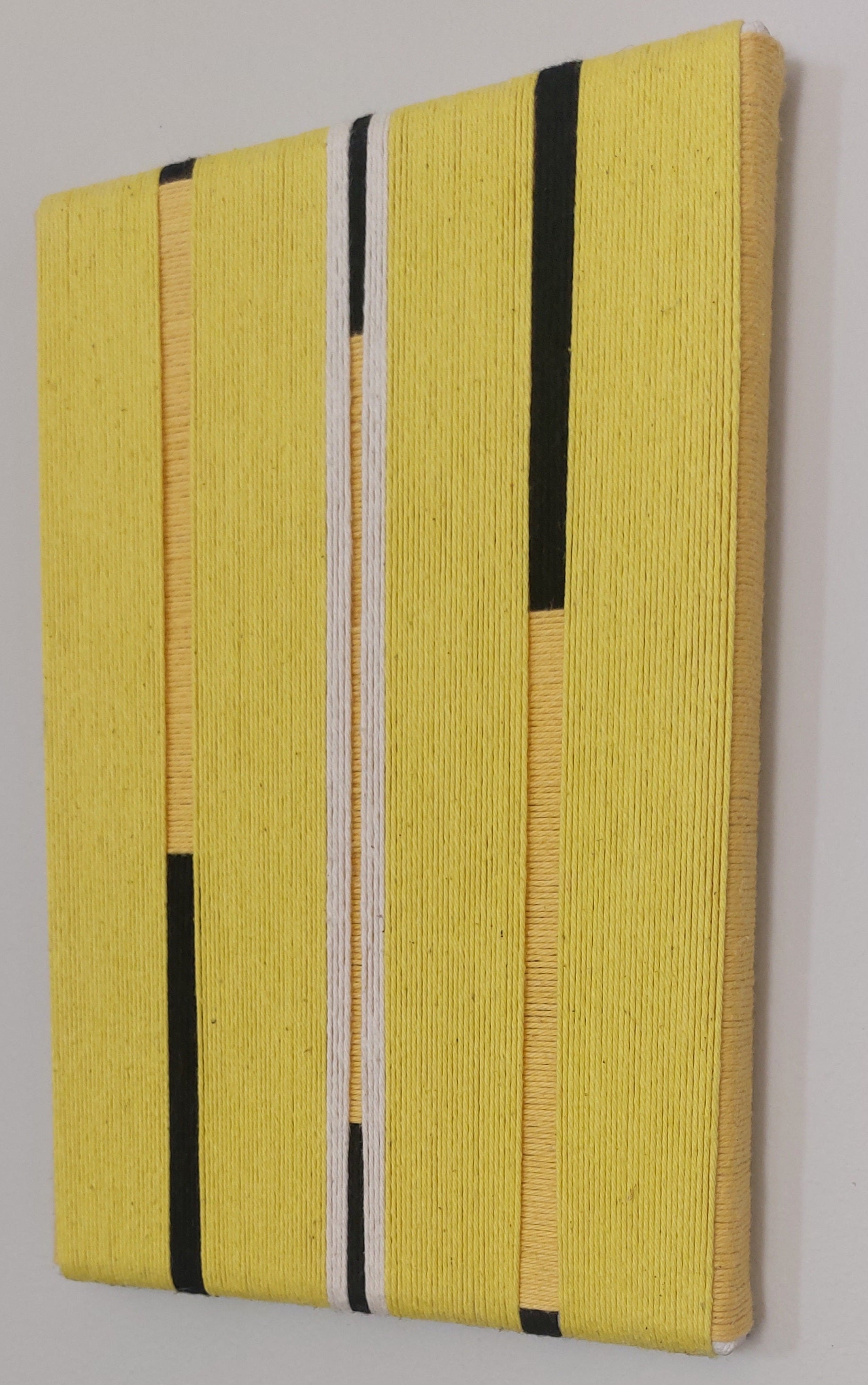 Yellow textile art with black and white stripes.