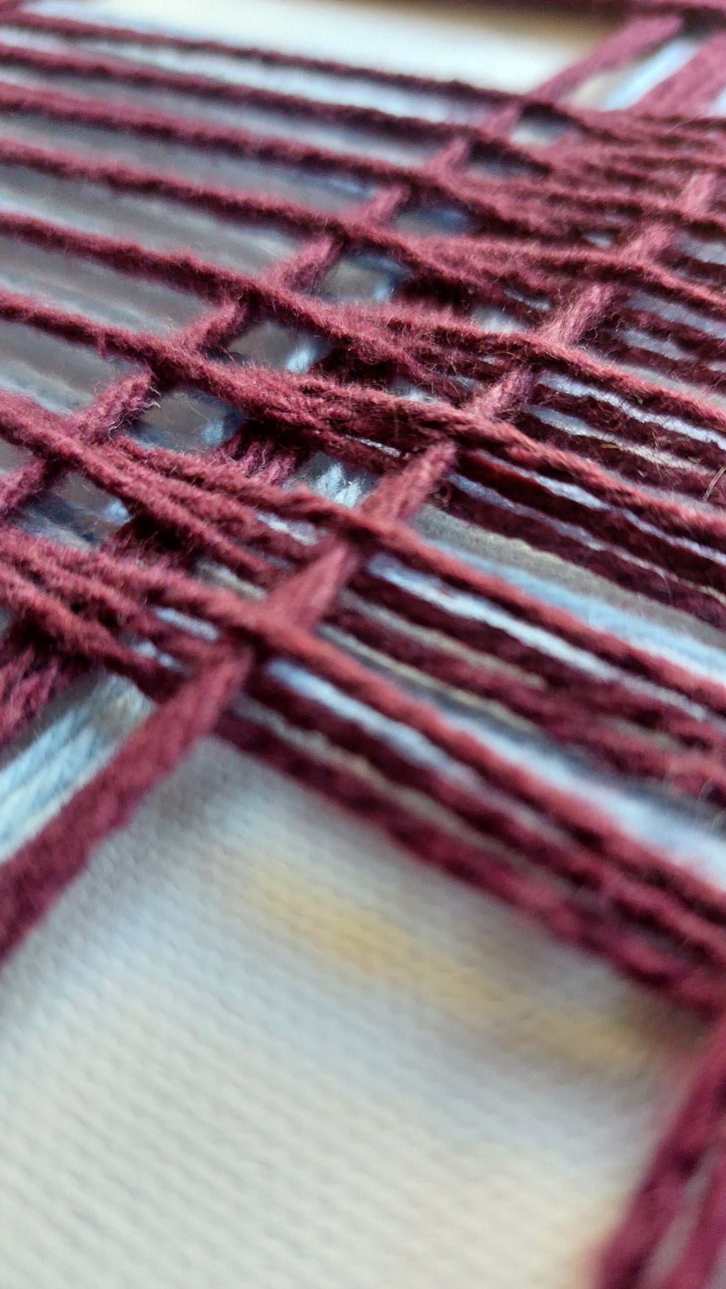Close-up of burgundy yarn woven over light blue yarn