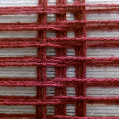 A close-up of a woven textile pattern showing dark red yarn interlaced with light blue yarn in a basketweave arrangement.