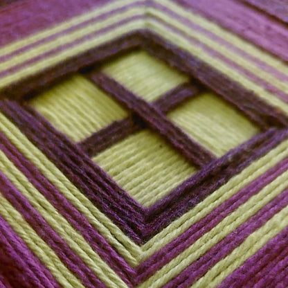 Close-up of a geometric woven textile art in purple and chartreuse.